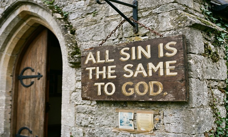 A sign with "All Sin is The Same to God" written on it.